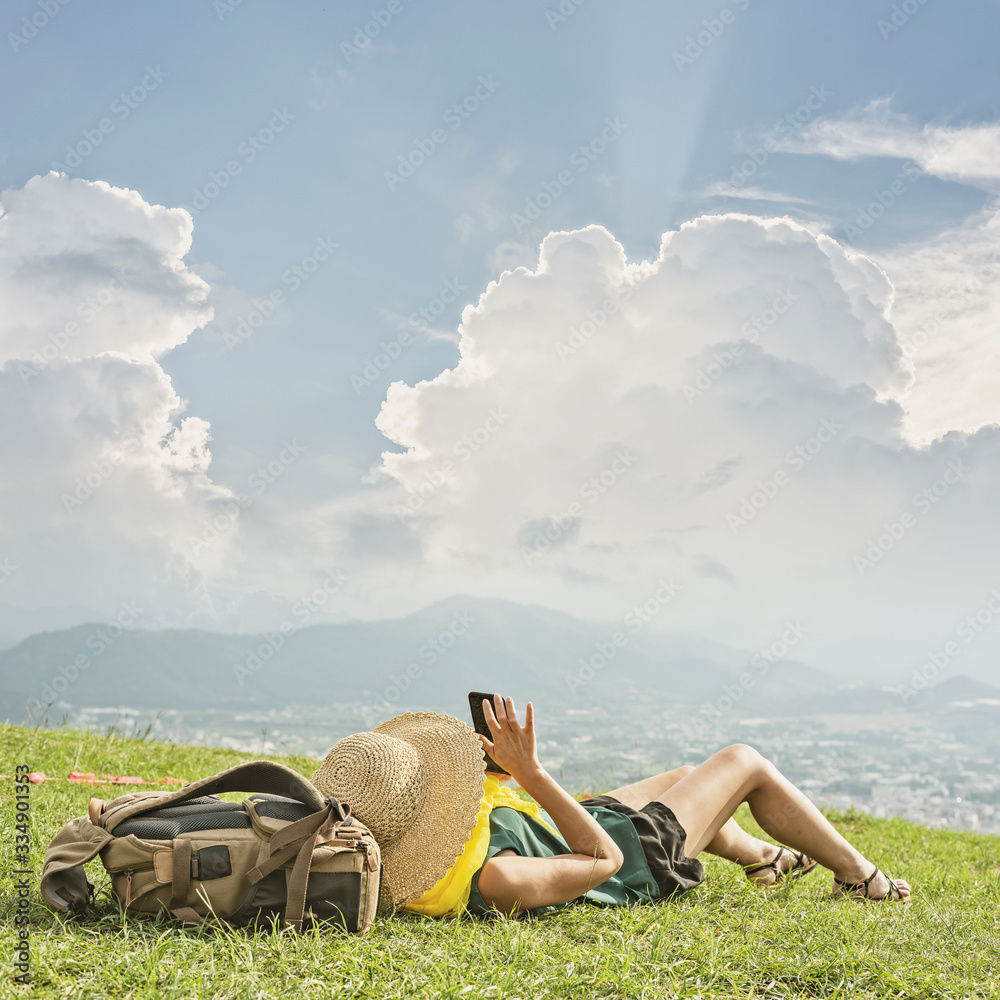 Wall mural woman lie on grassland and using cellphone