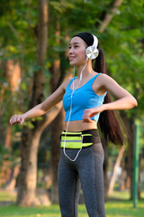 young woman doing exercise in the park and listening music