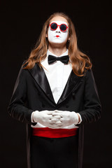 Portrait of male mime artist performing, isolated on black background. Man is standing straight...