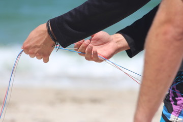 A kite boarder on the beach demonstrating how to untangle and prepare the kite lines. 