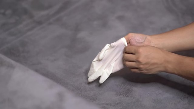 4k Asian man hand wearing white protective glove on one hand with gray background, self quarantine, stop illness from spreading, germ virus prevention, Corona virus 2019, COVID 19, healthcare medical