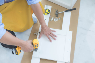 The mechanic assembled the furniture in the house according to the manual, along with the mechanic equipment. By hammering the nails Measuring with a tape measure Screwing the screw Drilling holes.