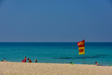 Phuket, Thailand Fab 17, 2018 : Red flags warn swimmers of severe hazards in the water with Many foreigners  tourists families and children come to play in the sea. Holiday season  Beachsafe concept