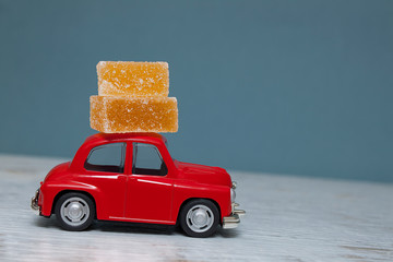 Red toy car with a stack of marmalade on the roof