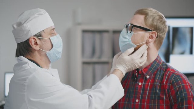 Doctor examining glands in neck of patient.