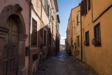Fototapeta na wymiar A narrow street between buildings in the historic town of Anguillara Sabazia in Italy
