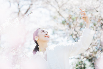 スマートフォンで桜を撮る女性