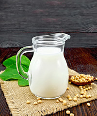 Milk soy in jug with beans on dark board