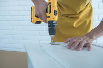 The mechanic assembled the furniture in the house according to the manual, along with the mechanic equipment. By hammering the nails Measuring with a tape measure Screwing the screw Drilling holes.