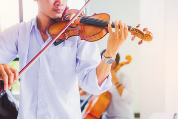 A musician man in white shirt is practicing the violin playing with the melodiousness. Selected focus. © Panumas