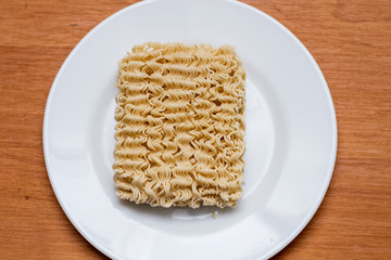 Instant noodles. standing on a white bowl before cooking.