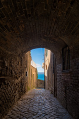 A pathway leading past a lake with houses in the town of Anguillara in Italy