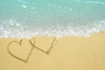 Two hearts drawn on the sand beach representing love, valentine, romance.