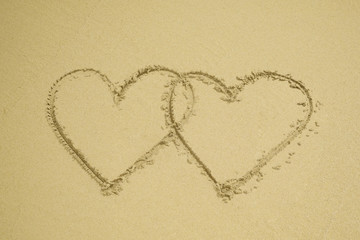 Two hearts drawn on the sand beach representing love, valentine, romance.