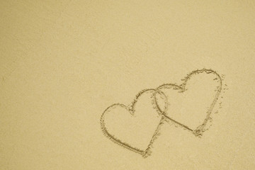 Two hearts drawn on the sand beach representing love, valentine, romance.