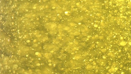 Golden Bubbles Slowly Rise Up. Golden background. Big and small golden bubbles oil inside gold...