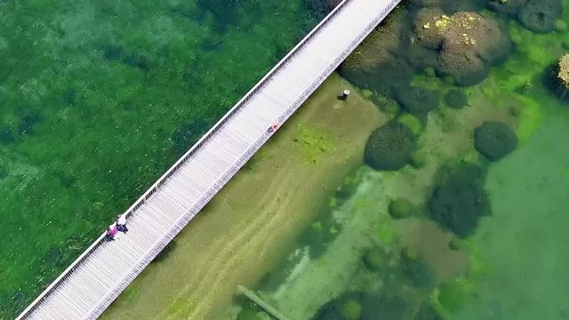 people walking on an bridge over a cristal clear lake