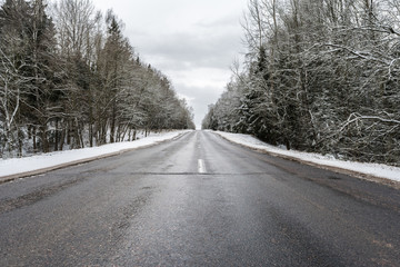 Winter asphalt road through the forest, standing, trees under a layer of snow