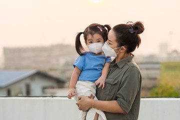 Asian mother and little young daughter wearing mask for prevent the spread of the Covid-19, Covic 19 virus protection concept in Thailand.
