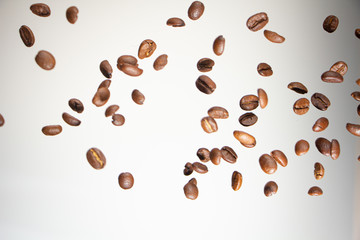 Falling coffee beans, in motion, on a white background. Selective focus.