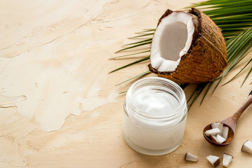 Face care. Coconut cream in glass jar on beige background copy space