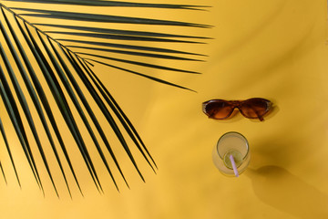 TOP VIEW  YELLOW BACKGROUND WITH GOGGLE AND LEMON COCKTAIL WINE GLASS LEAF