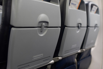 Row of airplane tray tables on seatbacks of a commercial aircraft.