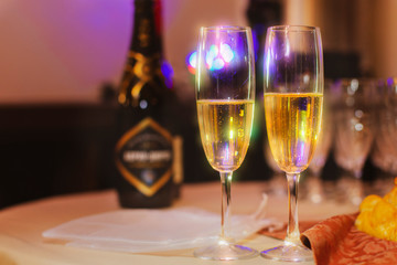 Two glasses with champagne on a restaurant background.