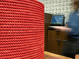 Waitress walks by register checkout and decorate red column in Asian restaurant