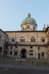 Fototapeta na wymiar Fountain in the inner yard of medieval palace Palazzo del Broletto with dome of the New Cathedral on background, Brescia, Lombardy, Italy.