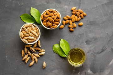 Almond oil - for cooking - in glass bowl near nuts on grey background top-down