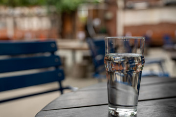 Full glass of water sitting on wooden picnic table in restaurant