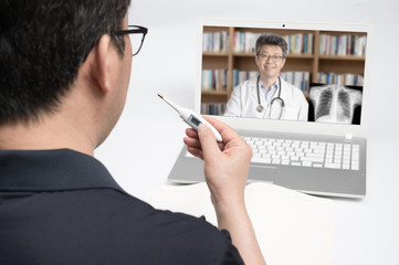 An Asian middle-aged man using a laptop to consult a doctor on telemedicine.