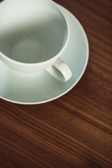 Leere, weiße Kaffeetasse auf einem hölzernen Tisch. Abstrakt, Tee oder Kaffee, Tasse mit Untertasse von oben