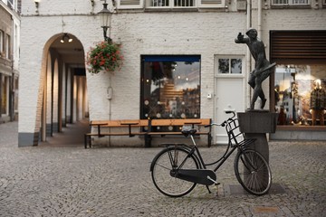 old bicycle parks on the street beside a sculpture in front of a shop
