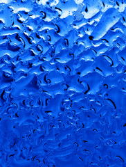 Blue drops of water on glass as an abstract background
