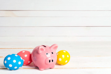 Piggy bank with eggs and daisies on a yellow background. Saving money for easter holidays. Copy space for text.