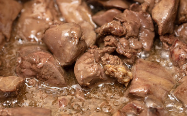 Chicken liver is fried in a pan.