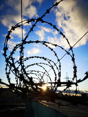 Barbed wire against the sky with clouds