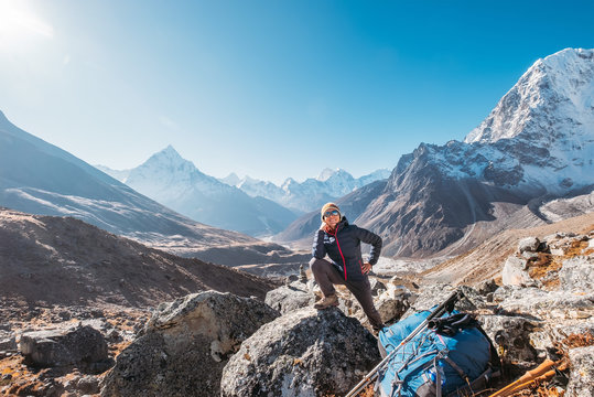 Young hiker backpacker female smiling and posing on Everest Base Camp route at Everest Memorial, Chukpi Lhara, Nepal. Ama Dablam mountain 6812m on background. Active vacations concept image.