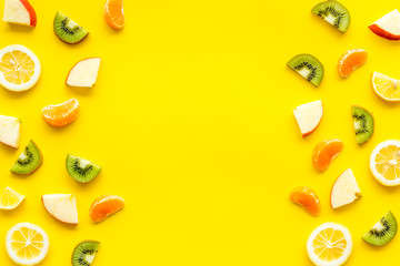 Slices fruites frame. Fruit salad concept with citruses, aplle and kiwi on yellow background top-down copy space