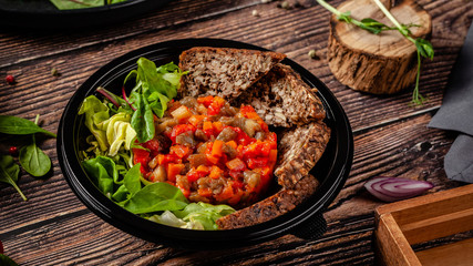 Balanced diet, keto diet. Tartare from vegetables, salad and whole grain rye bread. The concept of sports nutrition in disposable eco dishes.