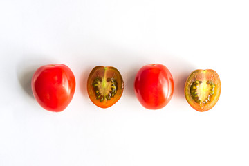 Ripe red and green cherry tomatoes in a row. Whole and halves of vegatbles on white background