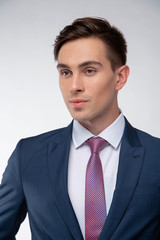 Young, handsome man in a blue suit in a white shirt with a tie on a white background in studio