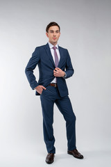 Young, handsome man in a blue suit in a white shirt with a tie on a white background in studio