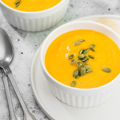 Creamy pumpkin cream soup with seeds. Autumn dish. Light grey background