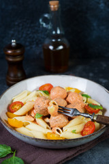 Penne pasta with meatballs tomatoes and sauce on a dark background