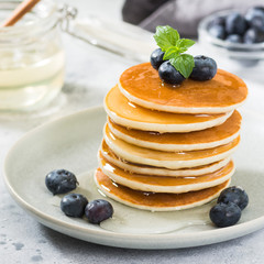 Sweet pancakes with honey and blueberries on the bright kitchen table	