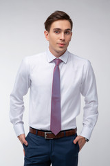 Fototapeta premium Young, handsome man in a white shirt with a tie on a white background in studio