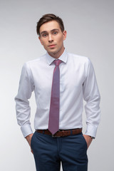 Young, handsome man in a white shirt with a tie on a white background in studio